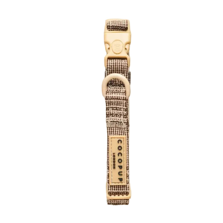 A close-up of a plaid dog collar with a tan buckle, metal D-ring, and a tan label reading 'COCOPUP' 