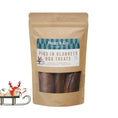 Load image into Gallery viewer, A stand-up kraft paper pouch of Hugo & Co. Pigs in Blankets dog treats, shown against a teal background with white snowflake graphics and a small holiday sleigh illustration at the lower left.
