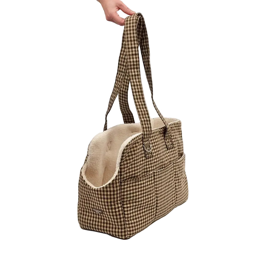 A brown and beige gingham tote bag with a cream sherpa lining, held by a hand against a plain white background.