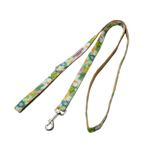 A fabric dog leash with a colorful floral pattern on a white background, featuring a tan inner lining and silver metal hardware.