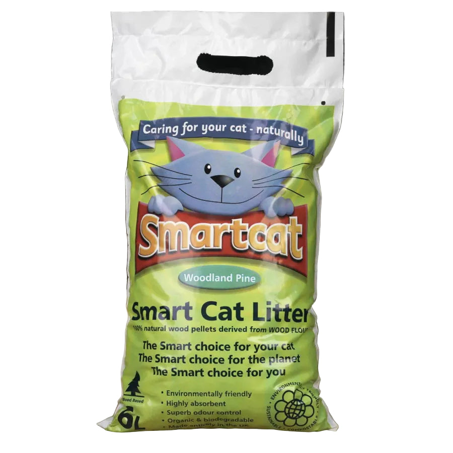 A 6kg bag of Smartcat Woodland Pine Smart Cat Litter, featuring a green and white packaging design with a cartoon cat illustration, set on a wooden floor against a dark background.