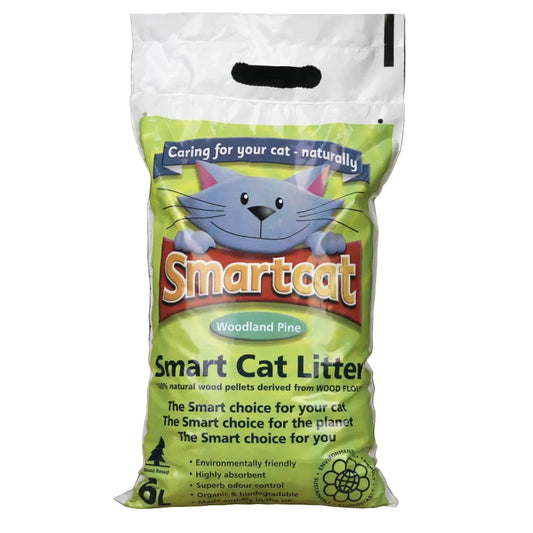 A 6kg bag of Smartcat Woodland Pine Smart Cat Litter, featuring a green and white packaging design with a cartoon cat illustration, set on a wooden floor against a dark background.