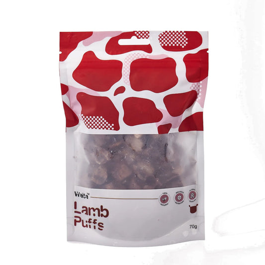 A 70g bag of Visita Lamb Puffs dog treats, featuring a red and white cow-print pattern on the top half and a clear window showing the brown puffs inside.